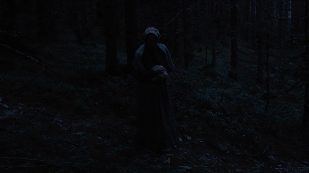 Hagazussa - Albrun regarde dans un point fixe dans le forêt le nuit.