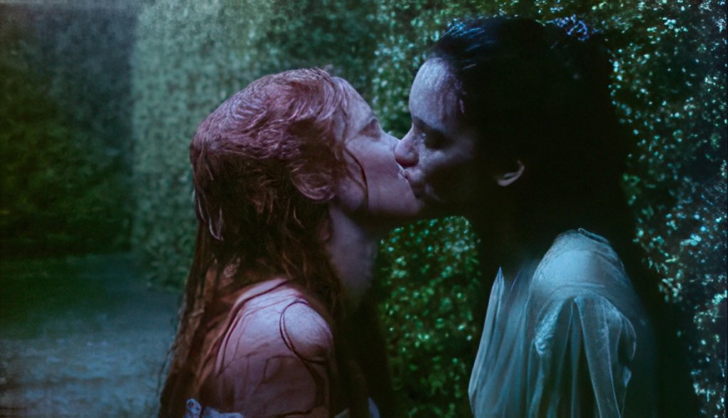 Scène intense de Dracula (1992) de Francis Ford Coppola : Mina (Winona Ryder) et Lucy (Sadie Frost) partagent un moment émotionnel dans un jardin nocturne enveloppé de brume.