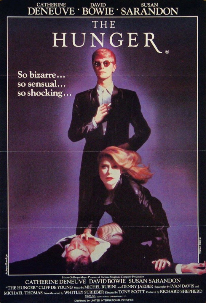 Affiche du film The Hunger (1983) avec Catherine Deneuve, David Bowie et Susan Sarandon : Ambiance sombre et sensuelle, David Bowie en costume élégant et Susan Sarandon en posture mystérieuse.