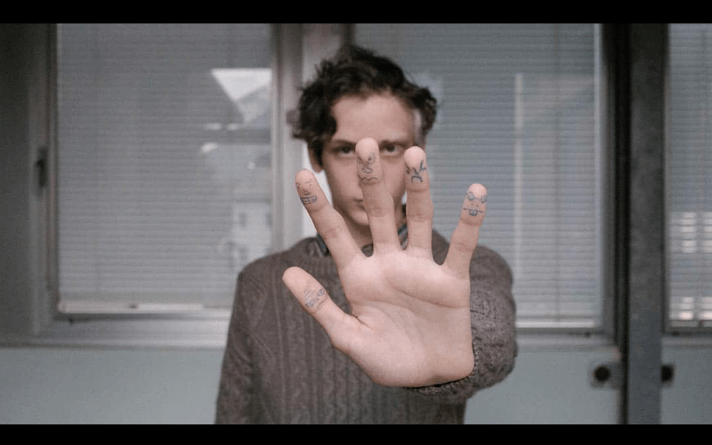 Matteo Corbin (Giulio Feltri) lève la main avec des dessins sur les doigts dans The Holy Boy